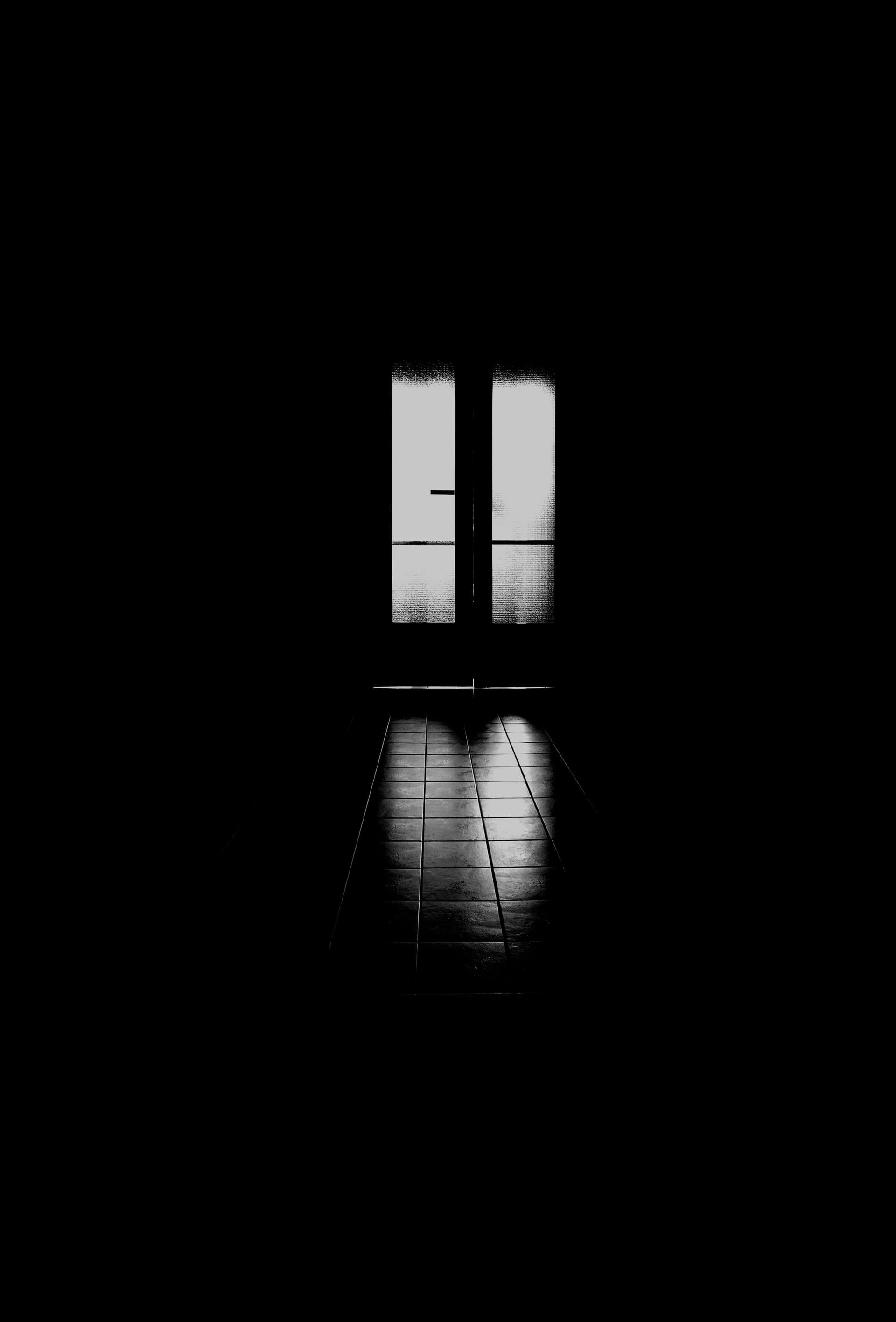 Black and white photograph of a doorway glowing at the end of a dark corridor